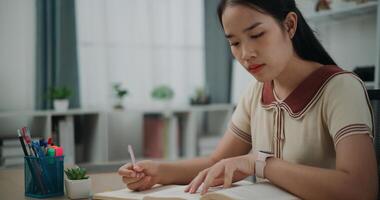 Selective focus, Female writer sitting at desk writing information on diary notebook while reading book at home, creative thoughts to journaling, idea and inspiration photo