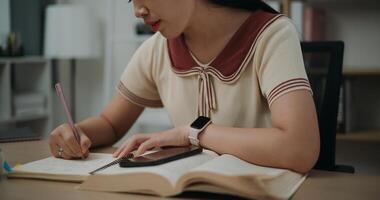 Selective focus, Hands of Female writer sitting at desk writing information on diary notebook while reading book at home, creative thoughts to journaling, idea and inspiration photo