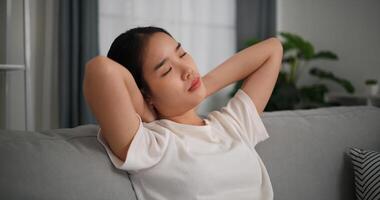 Selective focus, Happy young woman is practicing yoga and stretching her neck at home with eyes closed, relaxing body and mind alone on sofa in the living room,relaxation lifestyle photo