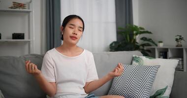 Selective focus, Relaxed young woman wear wireless headphones enjoying rest sitting on sofa in living room listening to music and dancing at home photo