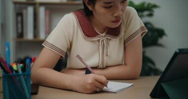 Selective focus, Front view,Female writer sitting at desk writing notes while working on tablet for online learning at home, creative thoughts to journaling, idea and inspiration photo