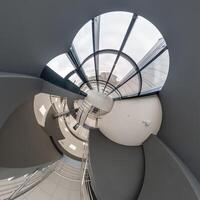 abstractly twisted into a spherical 360 panorama interior of a modern office with a hall staircase and panoramic windows photo