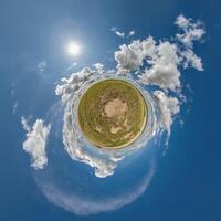 green tiny planet in evening blue sky with beautiful clouds. Transformation of spherical panorama 360 degrees. Spherical abstract aerial view. Curvature of space. photo