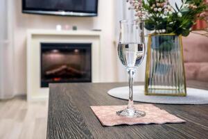 glass of sparkling wine or champagne on table with bouquet of flowers in front of fireplace photo