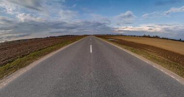 minuscule planète transformation avec courbure de espace parmi des champs sur gravier route dans ensoleillé journée avec ciel et duveteux des nuages video