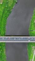 vertical accelerated video with aerial view on heavy traffic on a bridge with a wide multi-lane road across a wide river