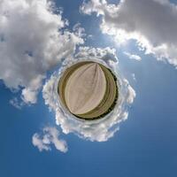 simple tiny planet without buildings in blue sky with beautiful clouds. Transformation of spherical panorama 360 degrees. Spherical abstract aerial view. Curvature of space. photo