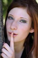 Young teen caucasian girl with finger to lips photo
