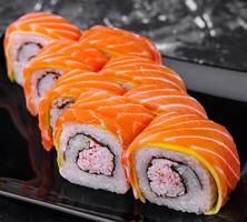 sushi rolls with salmon and crab on black plate photo