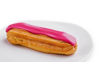 Eclair dessert with pink icing on plate photo