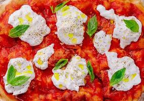Italian pizza with mozzarella cheese and tomato topped with fresh basil photo