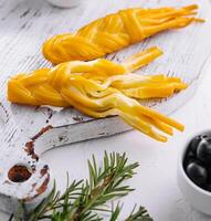 Smoked braided cheese on wooden board photo