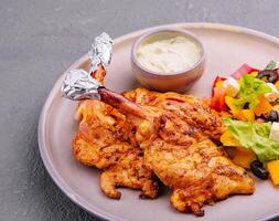 baked golden chicken drumsticks and Greek salad photo