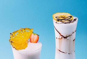 two glass cups of milkshake with dry pineapple and strawberries photo