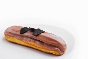 Eclair topped with chocolate on white plate photo