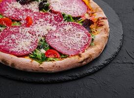 Delicious pizza with salami, arugula and tomatoes photo