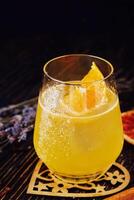 Glass of orange alcoholic drink with ice and slice of orange photo