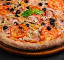 pizza with ham and mushrooms on black stone photo