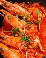 freshly cooked prawns in spicy tomato sauce and fish in batter photo