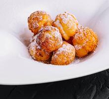 Profiteroles with powdered sugar close up photo