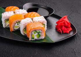 sushi rolls with salmon and crab on black plate photo