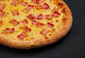 Pizza con tocino y queso en Roca tablero foto