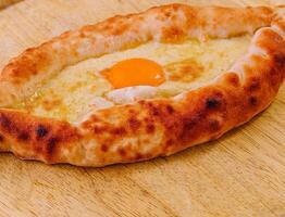 Ajarian Khachapuri, filled with cheese and topped with egg yolk photo