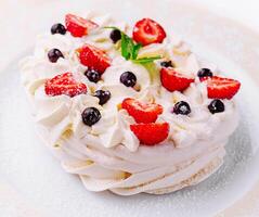 Pavlova cakes with cream and fresh berries on plate photo