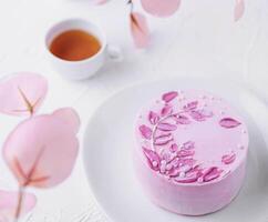 Piece of chocolate cake with pink cream and tea photo