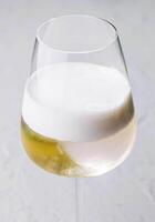 blanco cóctel con espuma en un vino vaso foto