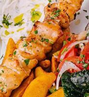 Chicken skewers with potatoes and tomato and onion salad photo