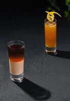 two different shots with alcoholic cocktails on dark stone photo