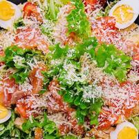 Salad with salmon, lettuce, boiled eggs, cherry tomatoes and parmesan cheese photo