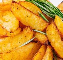 Baked potato wedges with rosemary close up photo