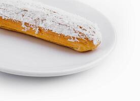 eclair in white glaze and coconut flakes photo