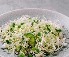 Spring vegan salad with cabbage, cucumber, green onion and peas photo