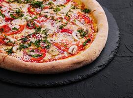 Delicious freshly baked pizzas on black plate photo
