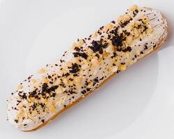 Eclair with cream and chocolate on plate photo