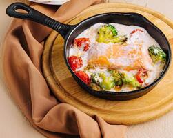 Fried salmon with creamy sauce on pan photo