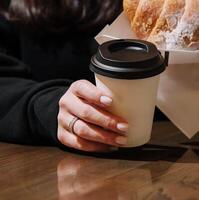 Woman holding a mug of coffee and a croissant photo