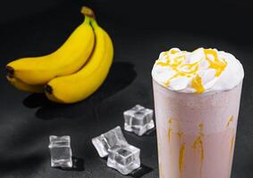 Delicious milkshakes on black stone with ice cubes photo