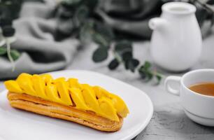 Fresh tasty eclair on white plate and cup of tea photo