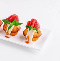 Vanilla cupcakes with strawberry on white plate photo