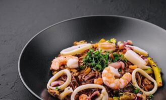 Buckwheat noodles with seafood in black plate photo