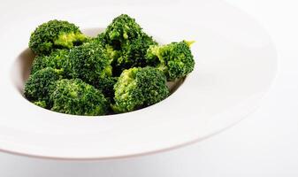 Fresh green broccoli in white circle plate isolated on white photo