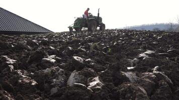 ein Erwachsene Mann fährt ein klein Traktor und pflüge ein Feld. landwirtschaftlich Aktivität. das Pflug schneidet das Land und bereitet vor es zum Aussaat Gemüse. ein Mann funktioniert im das Feld auf landwirtschaftlich Maschinen. 4k video