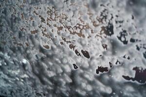 Car running through an automatic car wash with foam on glass. Abstract wet windshield background. photo