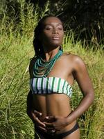 Young black woman half-length outdoors in green grass photo