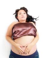 Young pregnant woman reclining on floor with hands photo