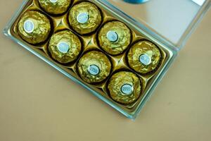 Bangkok, Thailand - March 9, 2024 Open box of Ferrero Rocher chocolates. Chocolate candies in a gold wrapper. photo